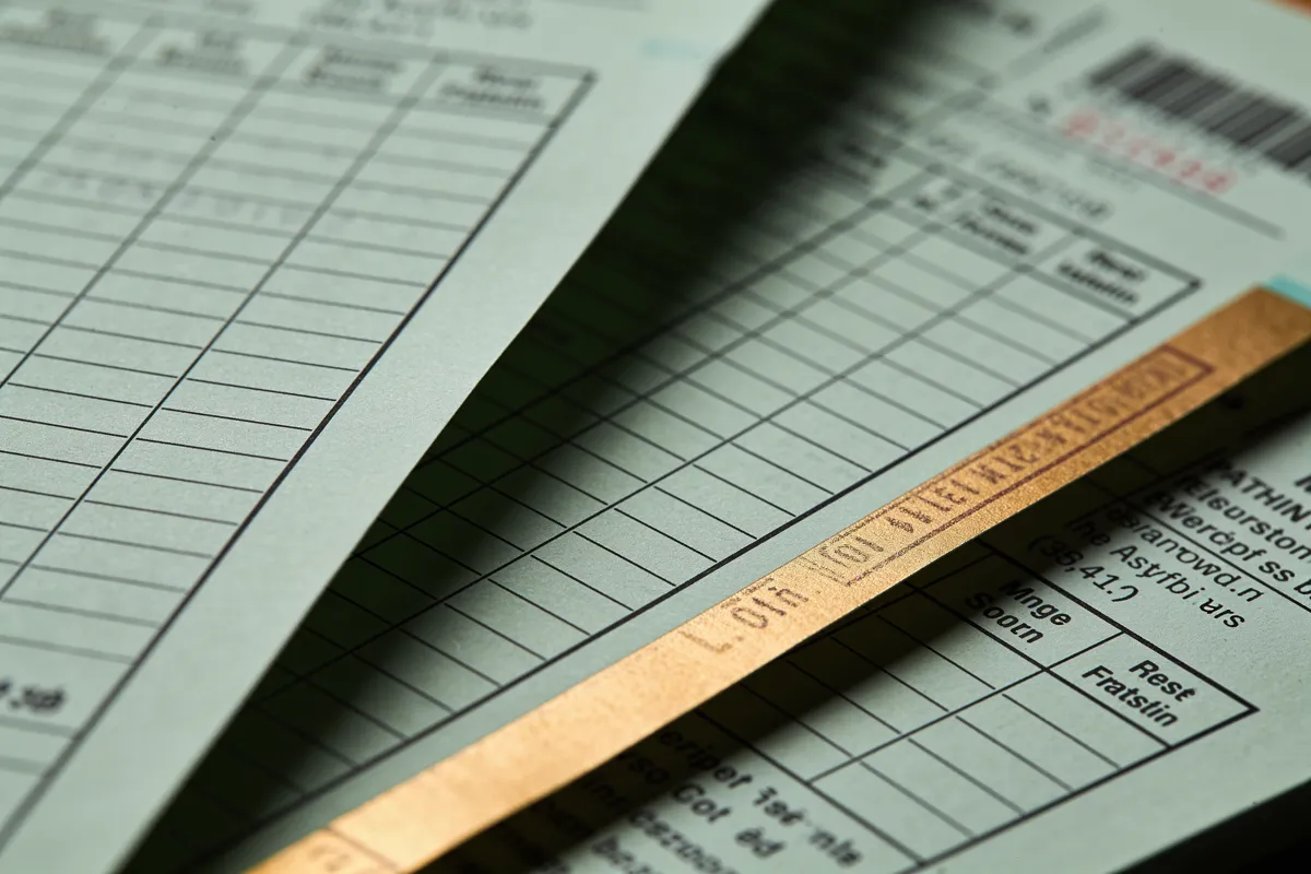 Macro of layered ruled ledger forms with a brass-toned paper edge